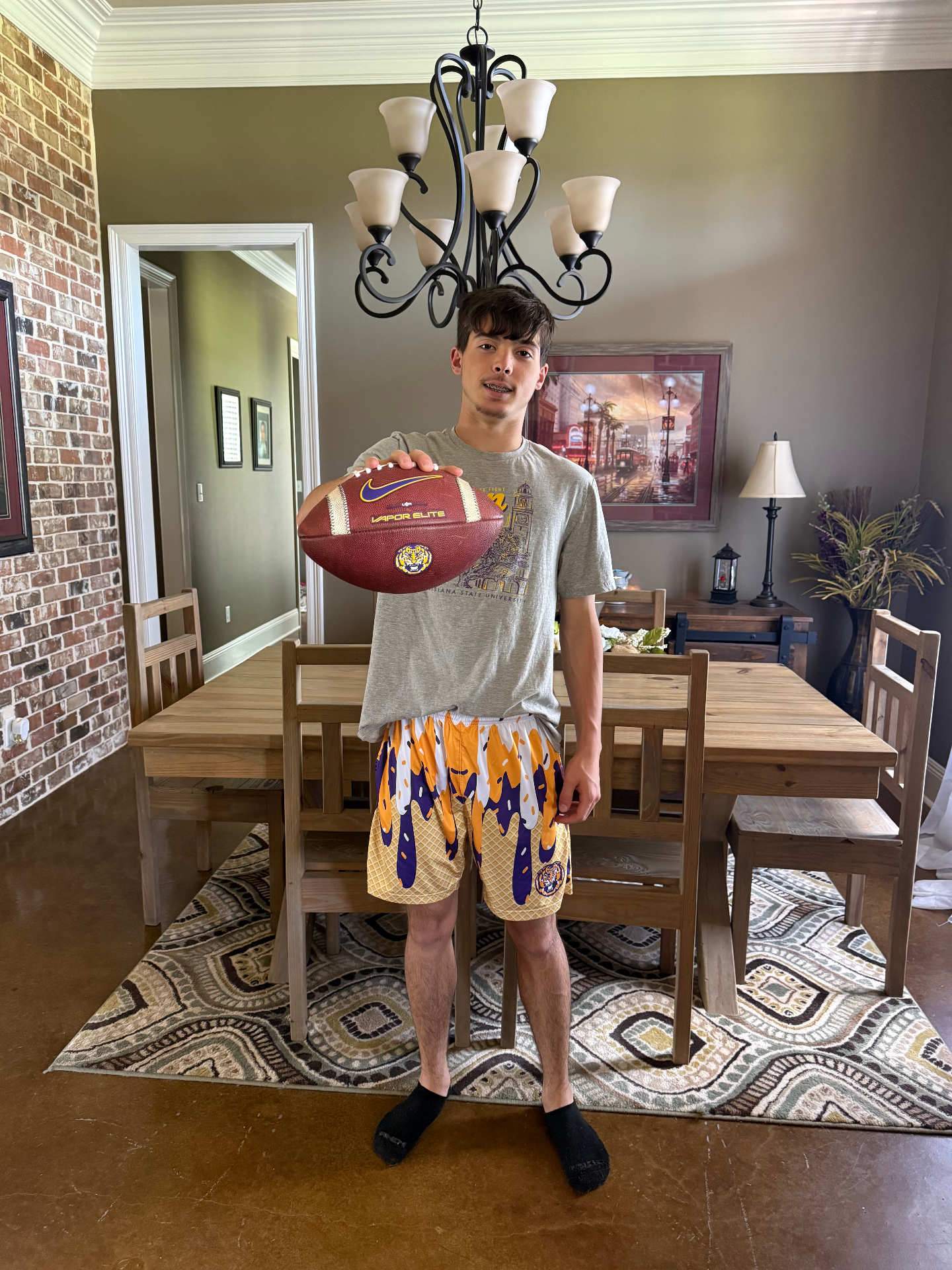 Teen holding LSU football in Parish Culture ice cream drip shorts